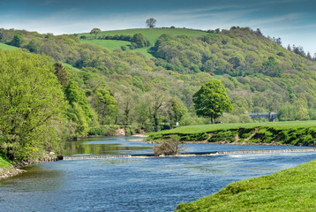 Obraz premium The river Lune near Lancaster below wooded slopes.