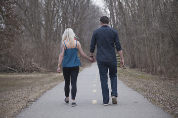 Couple walking holding hands on park trail