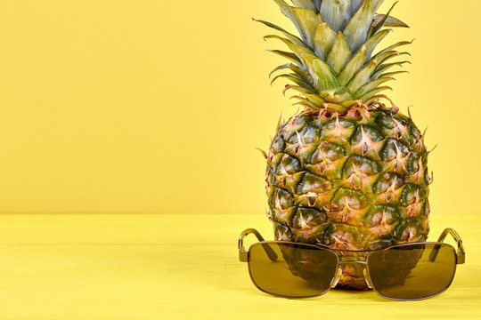 Ananas with sunglasses and copy space. Juicy fresh pineapple. Tips for healthy vacation.