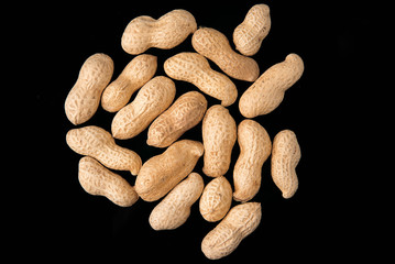 Roasted peanuts in shell on a black background, top view