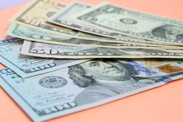 Banknotes of dollars of different value on a pink background