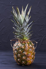 Pineapple in glasses on black background. Exotic pineapple fruit wearing eyeglasses on dark slate background.