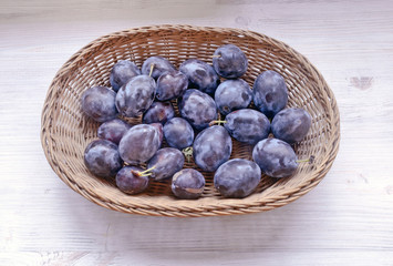 fresh prunes lie in a wicker basket