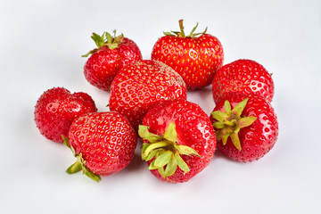 Juicy strawberries with green leaves. Heap of fresh strawberries on white background. Summer fruits harvest.
