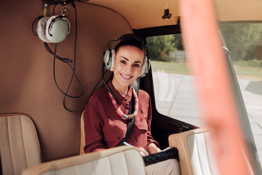 Happy passenger. Joyful merry woman sitting in helicopter and grinning to camera