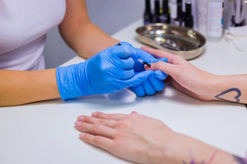 Obraz na płótnie Canvas Professional beautician applying nail polish to female nail in a nail salon.