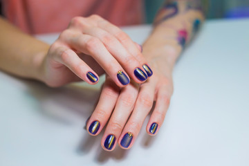 Finished purple shellac manicure, woman in nail beauty salon. Hands lie on white table and show the beautiful manicure