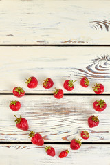 Heart shape from strawberries and copy space. Form of heart made of berries on white wooden background with copy space on top.