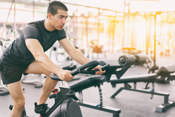 Fototapeta na wymiar Footage of a man working out in gym on the exercise bike, young man cycling in the gym. man exercising in fitness gym for good health.