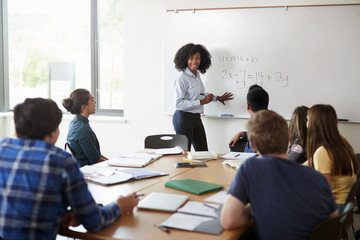 Female High School Tutor At Whiteboard Teaching Maths Class - Powered by Adobe