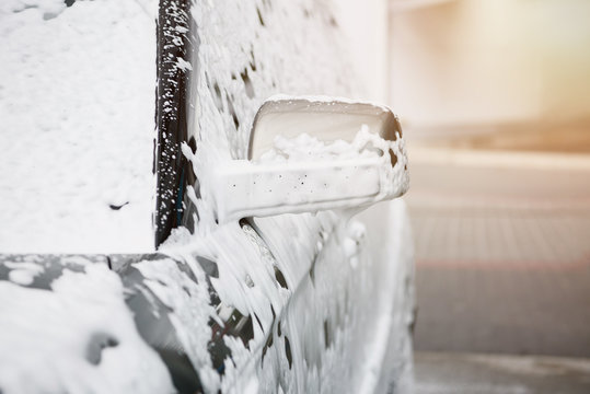 cropped image of car in white cleaning foam at car wash