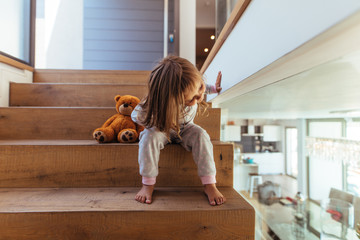 Little girl sitting on staircase at home