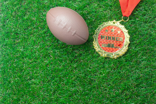 Table top view aerial image soccer or football season background.Flat lay accessories american ball and gold medal on the artificial green grass wallpaper.Free space for design text and content.