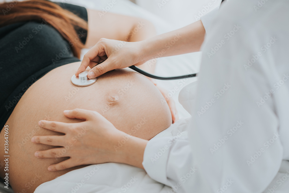 Wall mural doctor use stethoscope to check baby heartbeat in pregnant belly