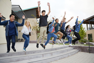 Group Of High School Students Jumping In Air Outside College Buildings