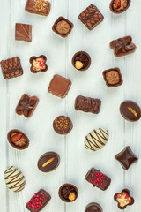Assorted chocolate sweets background. Mixed tasty chocolate candies on white wooden background, top view.