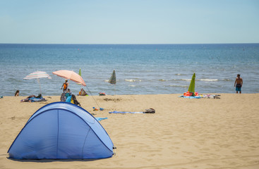 image of a camping tent on the almost deserted beach and the sea in the background