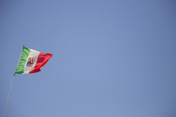 image of the Italian tricolor flag moved by the wind with the blue sky in the background