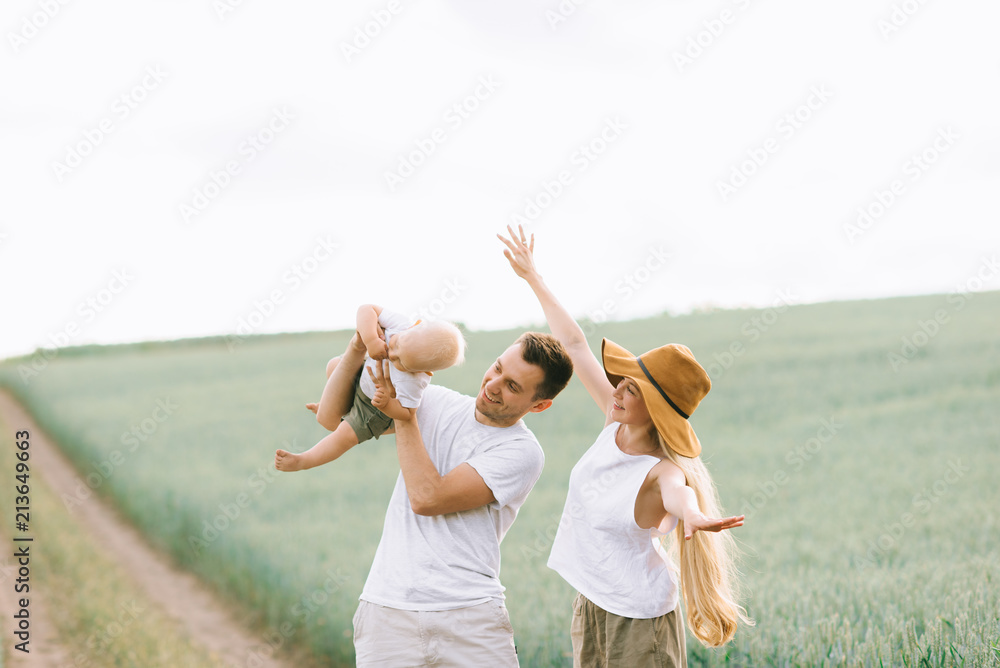 Wall mural a young family have a fun with their little baby in the field