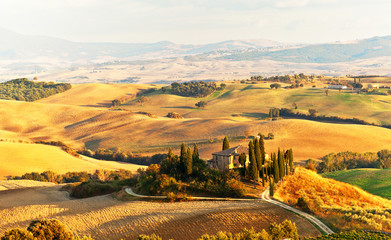 Italy. Pienza.  Beautiful Tuscany autumn rural landscape with cleaned fields and a farmhouse with...