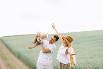 A young family have a fun with their little baby in the field