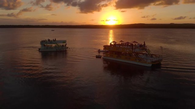 Boats filled with passengers watch the sunset on a river in Paraiba, Brazil