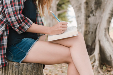 Nature, autumn, people concept. girls hands with pencil writing on notebook in park.