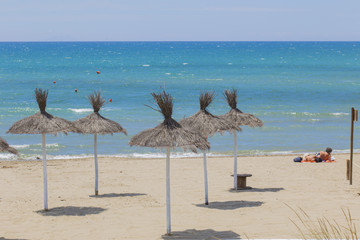 image of Caribbean beach umbrellas in straw, desolate with the sea in the background