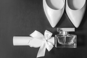flacon of fragrant perfume lying on the grey background near the white bridal shoes and the box...