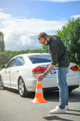 handsome man holding car insurance and putting safety cones on road