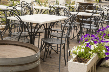 tables and chairs in black iron of an outdoor bar with vases of white and purple flowers