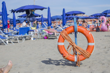 closeup of lifeguard orange life buoy on the beach with people in the background