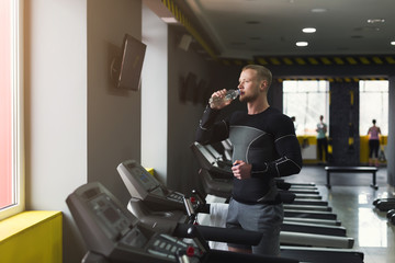 Male bodybuilder drinking water after workout