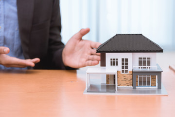 Businessman holding a toy house model in studio. Loan concept