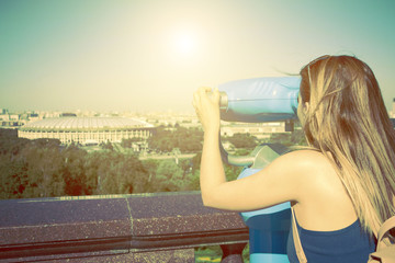 girl on the observation deck looking through binoculars at the Moscow