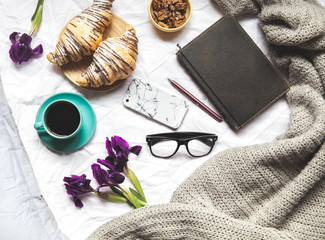 Breakfast in the bed. Morning, croissant, coffee, flowers and a notebook with a pen. Planning