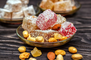 Traditional oriental sweets and traditional Turkish tea on a dark wooden background. Turkish desert-Rahat locum.