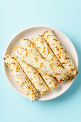 Rolled pancakes with berry filling on blue background with copy space