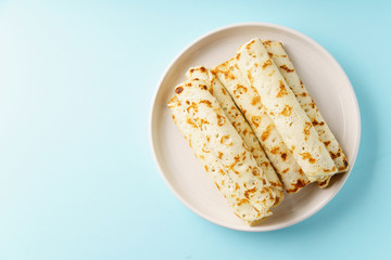 Rolled pancakes with berry filling on blue background with copy space