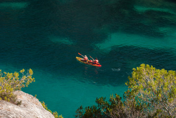 A family on a kayak in the sea of cove Macarelleta in Menorca