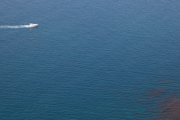 Aerial view of white motorboat sailing fast across smooth quiet sea. Luxury yacht cruising in tranquil turquoise ocean. Vacations, yachting, transportation, summer, seaside and recreation concept