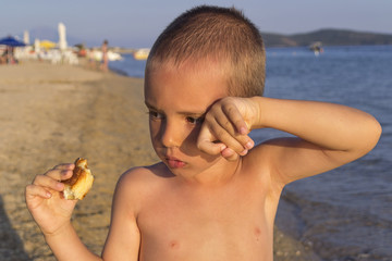 Boy eating croissant on beach