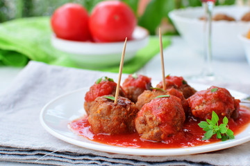 Meatballs in tomato sauce on white plate with greek basil herb