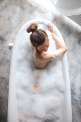 top view photo of active girl getting pleasure from bathtub with foam. holiday time