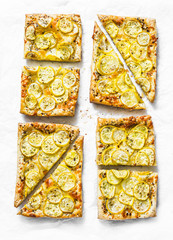 Yellow zucchini puff pastry mini tarts on a light background, top view. Tasty snack, tapas, appetizers