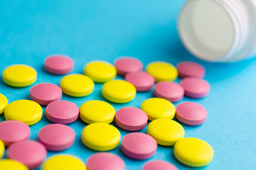 Heap of pills or tablets capsule plastic drugs bottle blue background. Drug prescription for treatment, Medicine pills Pharmaceutical medicament antibiotic, Pharmacy drugstore concept.