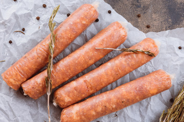 Raw sausages on a dark rustic metallic background. Meat sausages with spices on a baking paper. Copy space