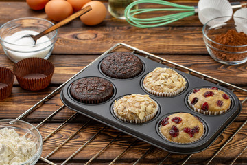 Different Muffins in bakeware or muffin pan on broun wooden background. Basic muffin recipe. Homemade muffins for breakfast or dessert.