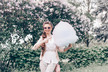 Portrait of a Smiling Beautiful Lady in Sunglasses Holding Cotton Candy at Park and Happily Looking in Camera. Film Color and Toning