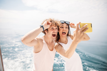 Happy caucasian couple taking selfie photo over beautiful sea background. Romantic lovers, woman...